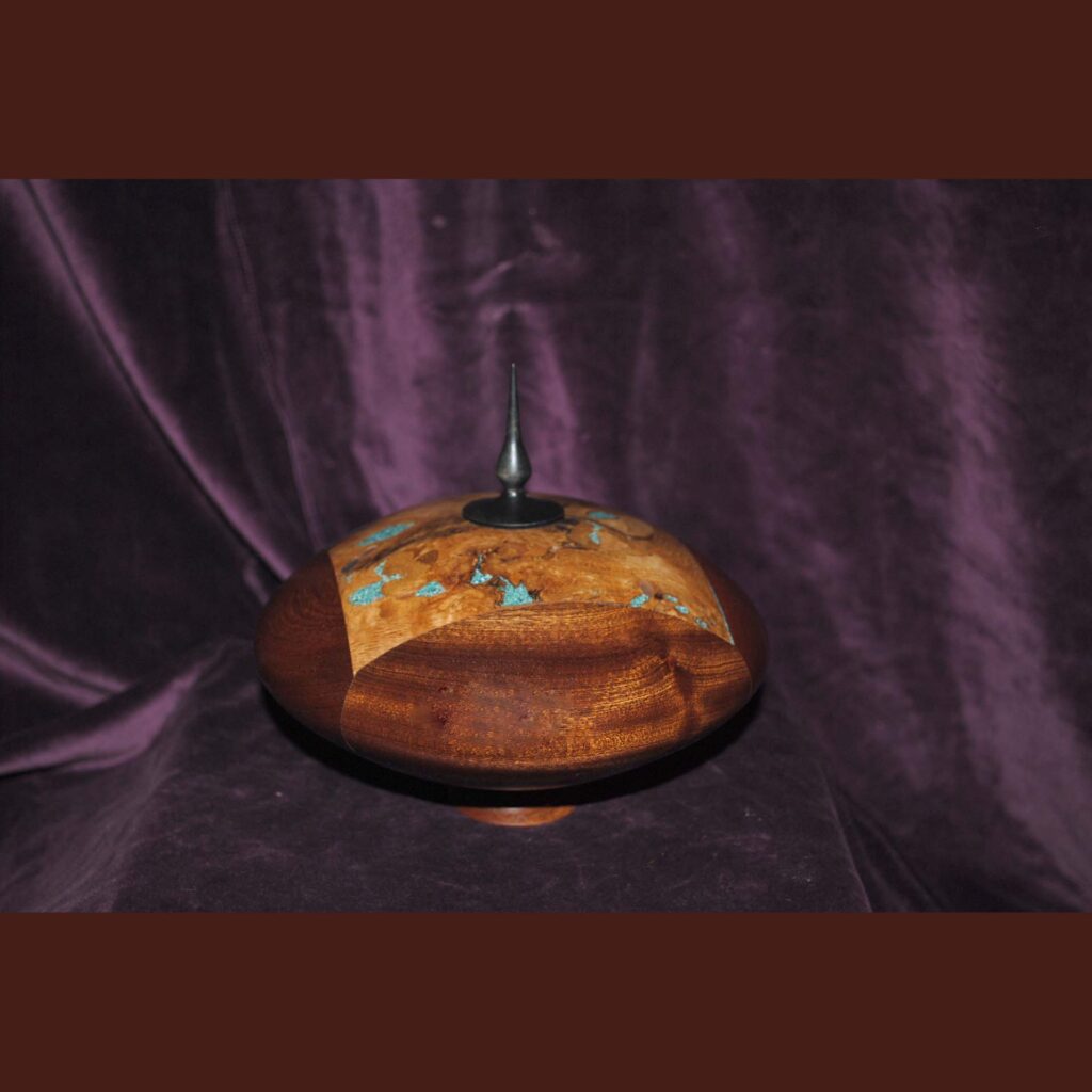 Round Wooden Lidded Vessel with Decorative Inlay and Black Finial Displayed Against a Purple Backdrop